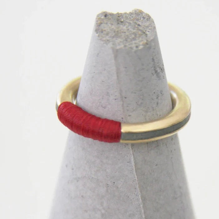  A contemporary and chic HADAS SHAHAM Red Thread Stacking Ring made from gold plated brass, concrete, and red nylon thread.